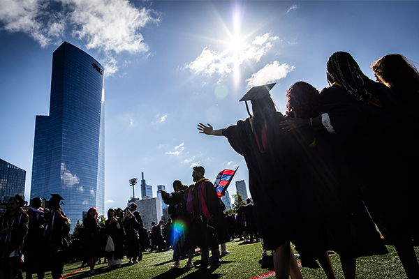 Group of students facing away posing for a photo with the sky in the background.