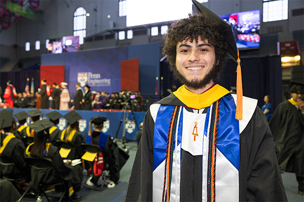 Student smiling at Commencement ceremony proudly showing his regalia
