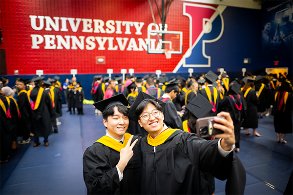Two students smiling in front of University of Pennsylvania at Commencement